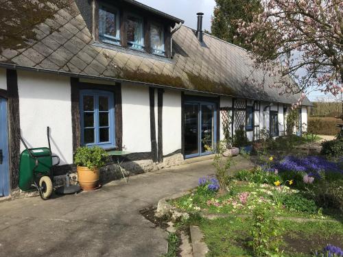 una casa blanca y negra con flores delante en Charmante villa normande à 1h de la mer, 1h30 de Paris, en Le Tronquay