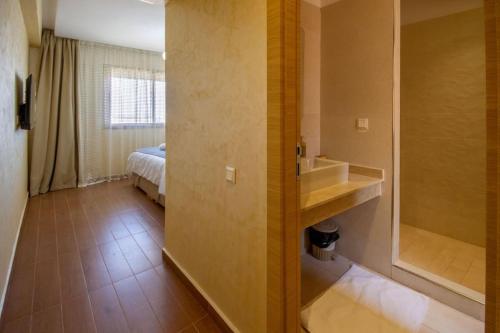 a bathroom with a tub and a sink and a bed at Appartement luxueux Coralia avec piscine in Marrakesh