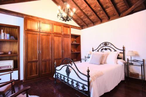 sypialnia z łóżkiem z drewnianymi szafkami i żyrandolem w obiekcie El Convento II, tranquilidad y vistas únicas w mieście San Andres y Sauces
