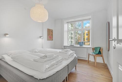NABO Hotel Apartments في كوبنهاغن: غرفة نوم بيضاء مع سرير كبير ونافذة