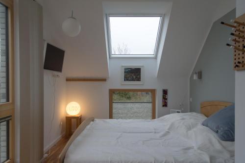 sypialnia z dużym białym łóżkiem i oknem w obiekcie Ferienhaus Schleiharmonie w mieście Ulsnis