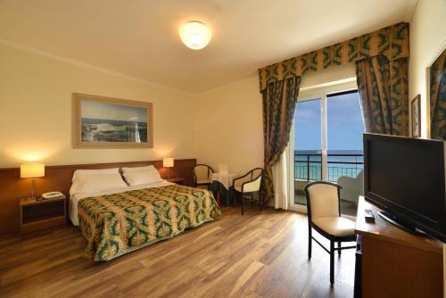 ein Hotelzimmer mit einem Bett und einem Flachbild-TV in der Unterkunft Hotel Europa & Concordia in Alassio