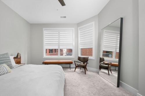 a bedroom with a bed and a desk and two windows at Park 202 Downtown in the Heart of Traverse City in Traverse City