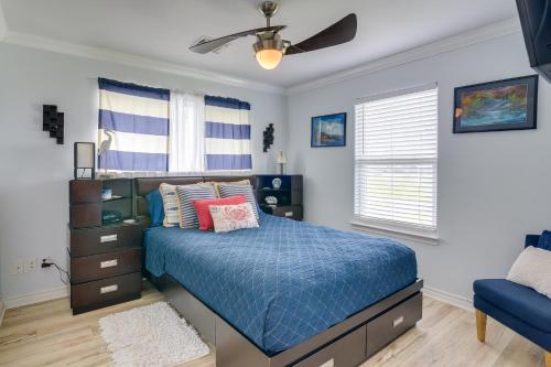 Schlafzimmer mit einem blauen Bett und einem Deckenventilator in der Unterkunft Galveston Escape with Entertainment Patio and Deck! in Galveston