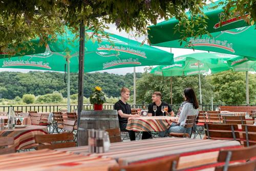a group of people sitting at a table under green umbrellas at Gasthof zum Schiff in Obereisenheim