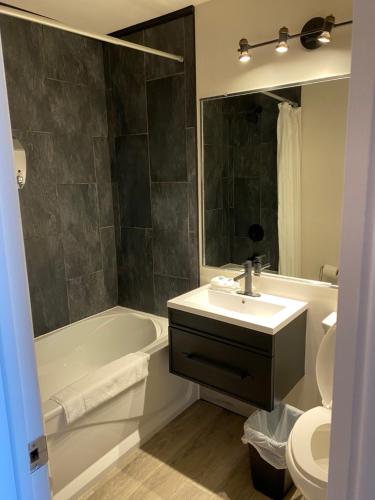 a bathroom with a sink and a tub and a toilet at Hébergement Fort Prével in Saint-Georges-de-Malbaie