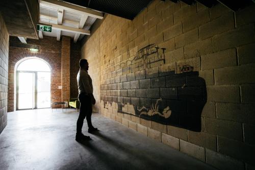 a man walking in a room with a brick wall at Smaltovňa Lofty in Lučenec