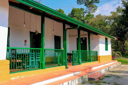 une maison avec des ornements verts et jaunes et une terrasse couverte dans l'établissement La Hacienda, à San Gil