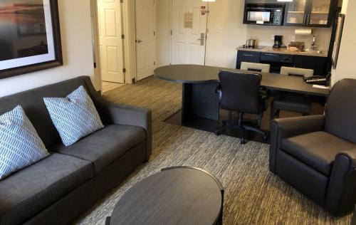 Candlewood Suites Greenville NC, an IHG Hotel في غرينفيل: غرفة معيشة مع أريكة وطاولة
