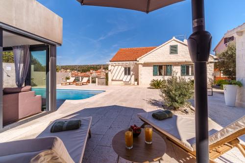 un patio con mesa, sillas y sombrilla en Villa TM with private heated pool, poolhouse & private garage en Milna