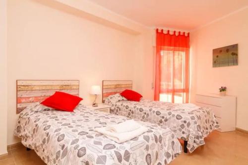 2 camas en una habitación blanca con almohadas rojas en Piso precioso con vistas al mar., en Nerja