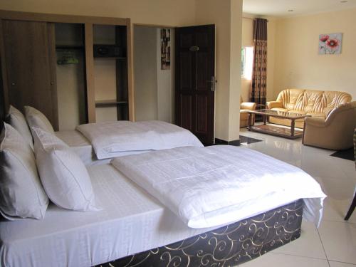 1 Schlafzimmer mit 2 Betten und weißer Bettwäsche in der Unterkunft Stipp Hotel Gisenyi in Gisenyi