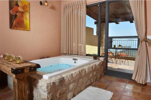 uma banheira de hidromassagem num quarto com varanda em קאמי מלון בוטיק עם ממ"ד - Kami Boutique Hotel em Safed