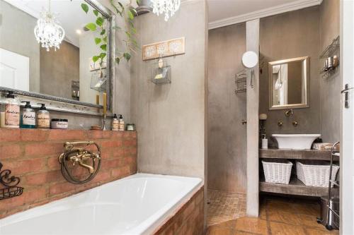 bagno con ampia vasca e lavandino di Ambiance Guesthouse a Pretoria