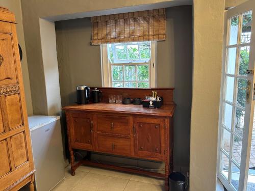 baño con tocador de madera y ventana en Battiss Guest House, en Pretoria