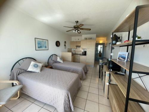 une chambre avec deux lits et un ventilateur de plafond dans l'établissement Charmant T2 avec balcon, clim et animaux admis à Balaruc-les-Bains - FR-1-503-85, à Balaruc-les-Bains