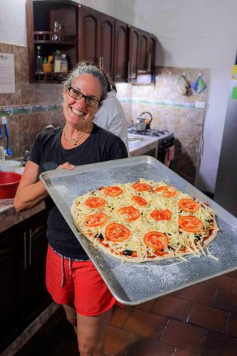 a woman standing in a kitchen holding a large pizza at La Hacienda in San Gil
