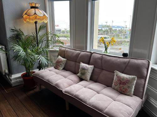 a brown couch in a living room with a window at The Commodore Rooms & Relaxation in Paignton