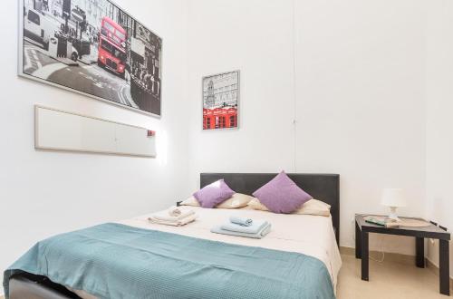um quarto com uma cama com travesseiros roxos em L'Appartamentino Holiday Home em Lecce