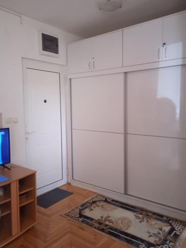 a room with white cabinets and a desk and a television at Benvenuto in Vrnjačka Banja