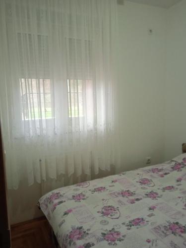 a bedroom with a bed and a window with white curtains at Benvenuto in Vrnjačka Banja