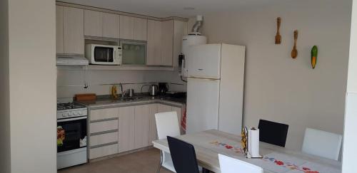 a kitchen with a white refrigerator and a table with chairs at Casa calida y acogedora, Capital Mendoza in La Cieneguita