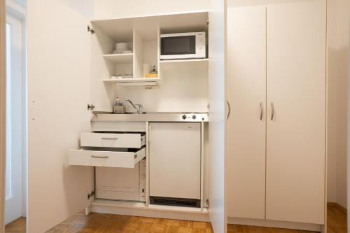 a small kitchen with white cabinets and a microwave at Central living - Stephansdom Apartments in Vienna