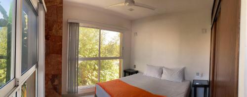 a bedroom with a bed and a large window at Palmas de Chahue in Santa Cruz Huatulco