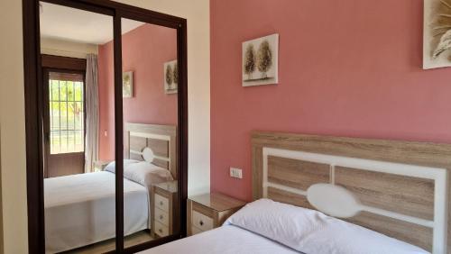 a bedroom with two beds and a mirror at HOTEL NUEVO ESPARTINAS in Espartinas