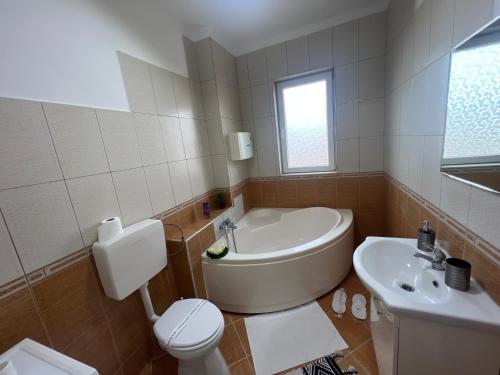 y baño con bañera, aseo y lavamanos. en Miha Residence, en Arad