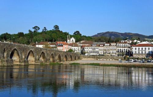 un puente sobre un río con una ciudad al fondo en Pertinho do Rio, en Ponte de Lima