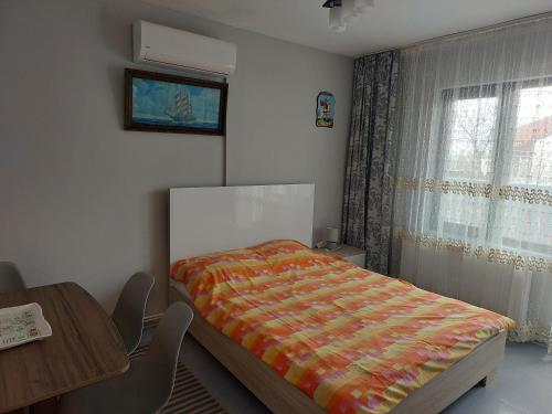 a bedroom with a bed and a table and a window at EL Mar in Eforie Sud