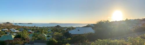 a view of a town with the sun setting over the water at SUNSEEKER SXM - Luxury Guest House 4 stars - Amazing Sea View Pinel - Tintamarre in Orient Bay