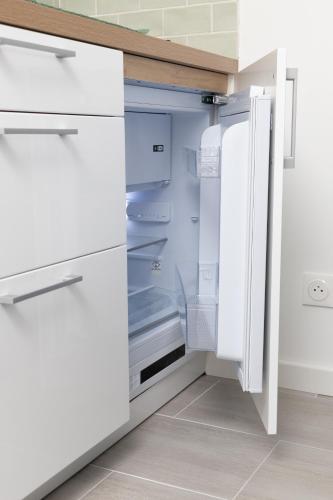 an empty refrigerator with its door open in a kitchen at Studio fonctionnel proche de la frontière in Loisin