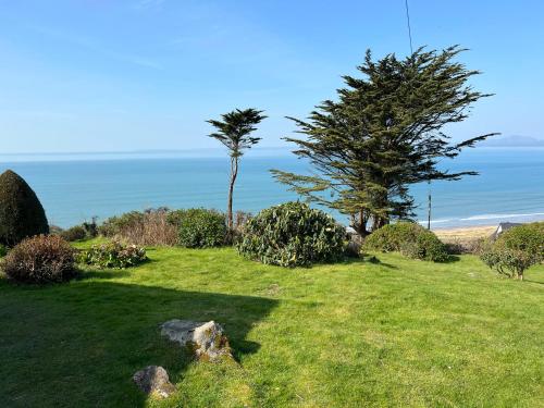 a green field with two trees and the ocean at Sibrwd Y Mor in Harlech