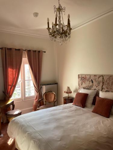 a bedroom with a bed with a chandelier and a window at Hôtel Château des Jacobins in Agen