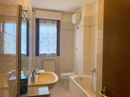 y baño con bañera, lavabo y aseo. en Aria di casa affittacamere, en Badesse