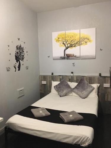 a bedroom with a bed with two paintings on the wall at Queens Guesthouse Manchester in Manchester