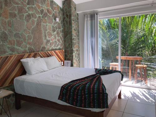 a bedroom with a bed and a large window at Palmas de Chahue in Santa Cruz Huatulco