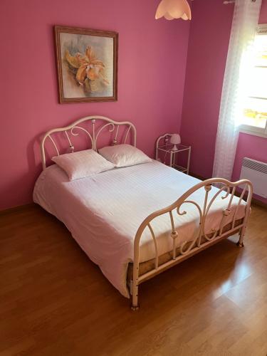 1 dormitorio con 1 cama blanca en una pared rosa en Logement, en Vic-Fezensac