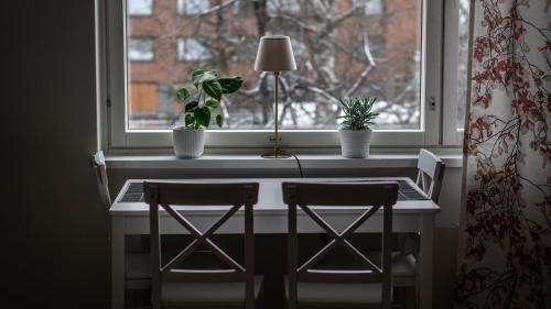 a table with two chairs and a window with two plants at Pyynikin Rauha in Tampere