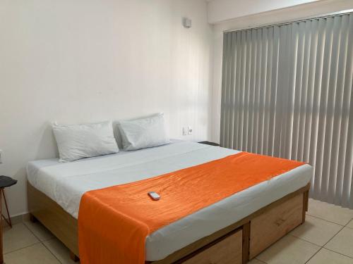 a bedroom with a bed with an orange blanket on it at Palmas de Chahue in Santa Cruz Huatulco