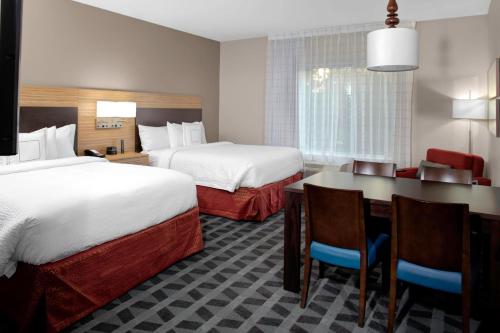 a hotel room with two beds and a table and chairs at TownePlace Suites by Marriott Albany in Albany
