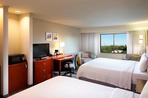a hotel room with two beds and a desk with a television at Courtyard by Marriott Brownsville in Brownsville