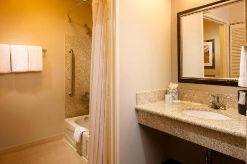 a bathroom with a sink and a mirror and a tub at Courtyard by Marriott Brownsville in Brownsville