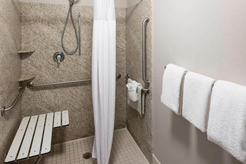 a bathroom with a shower with white towels at Courtyard by Marriott Brownsville in Brownsville