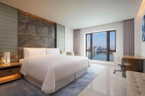 a bedroom with a large white bed and a window at The Westin Haikou in Haikou