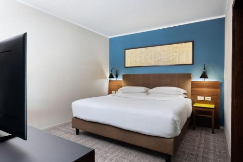a bedroom with a large bed with a blue wall at Four Points Sheraton Bolzano Bozen in Bolzano
