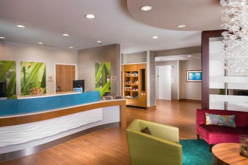 een hotellobby met een receptie en een rode stoel bij SpringHill Suites by Marriott Bentonville in Bentonville