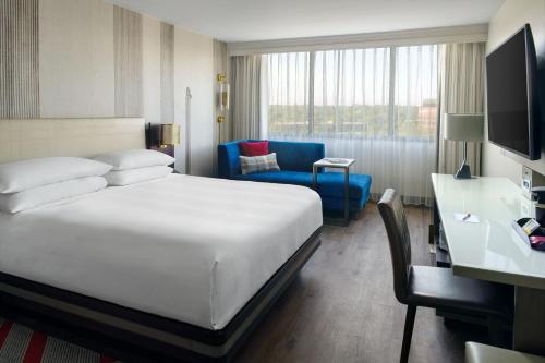 オーバーランド・パークにあるMarriott Kansas City Overland Parkの大きなベッドと椅子が備わるホテルルームです。